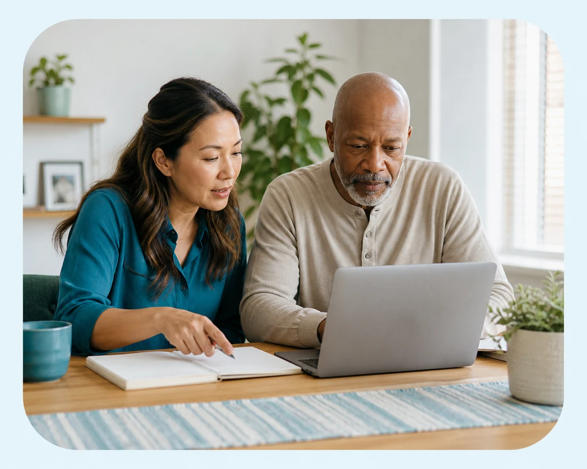Two people comparing information together on a laptop and notebook at home.